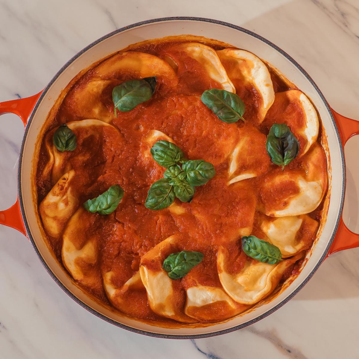 Capeletes ao molho de tomate com folhas de manjericão, em panela esmaltada