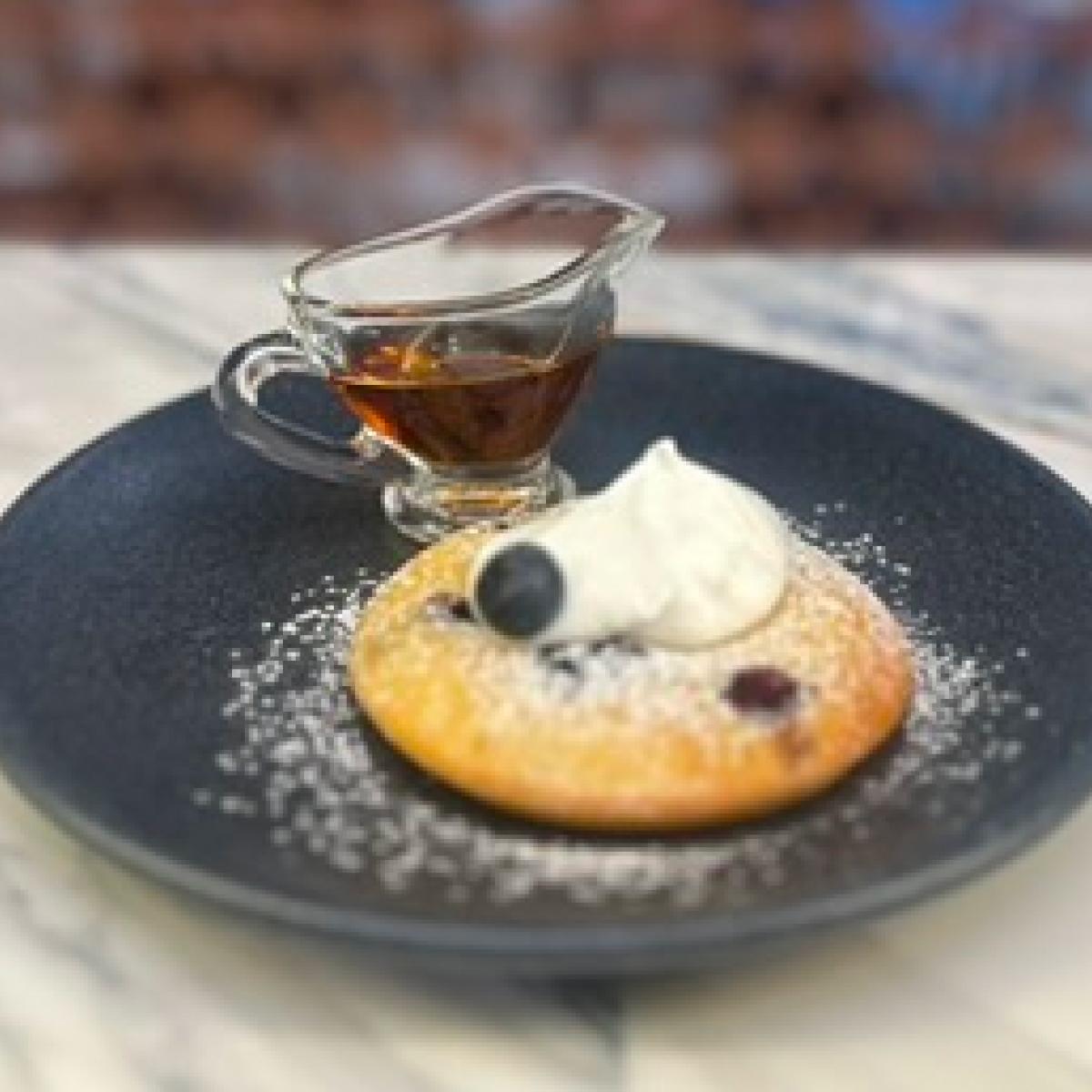 Sobremesa empratada com chantilly e mirtilo, com calda servida à parte