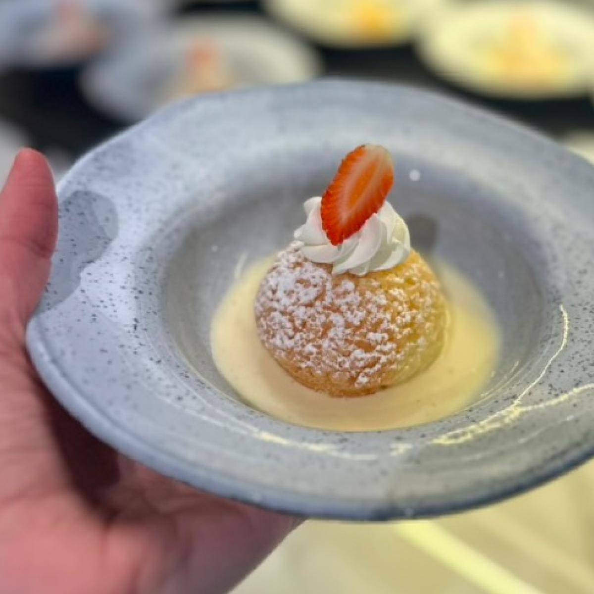 Bolinho doce polvilhado com açúcar, morango e chantilly sobre creme